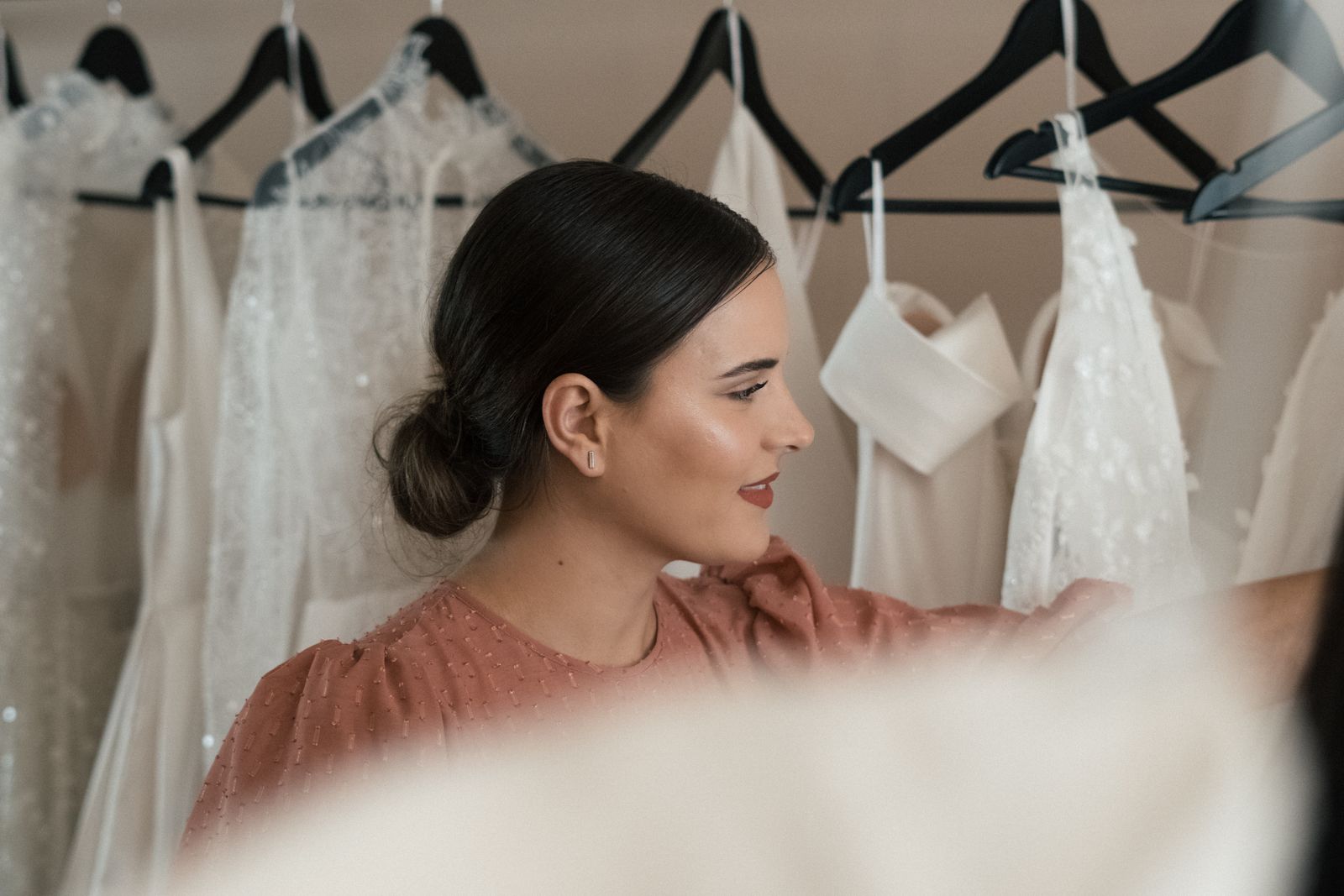 Gowns on a rail beside a tall mirror in the boutique
