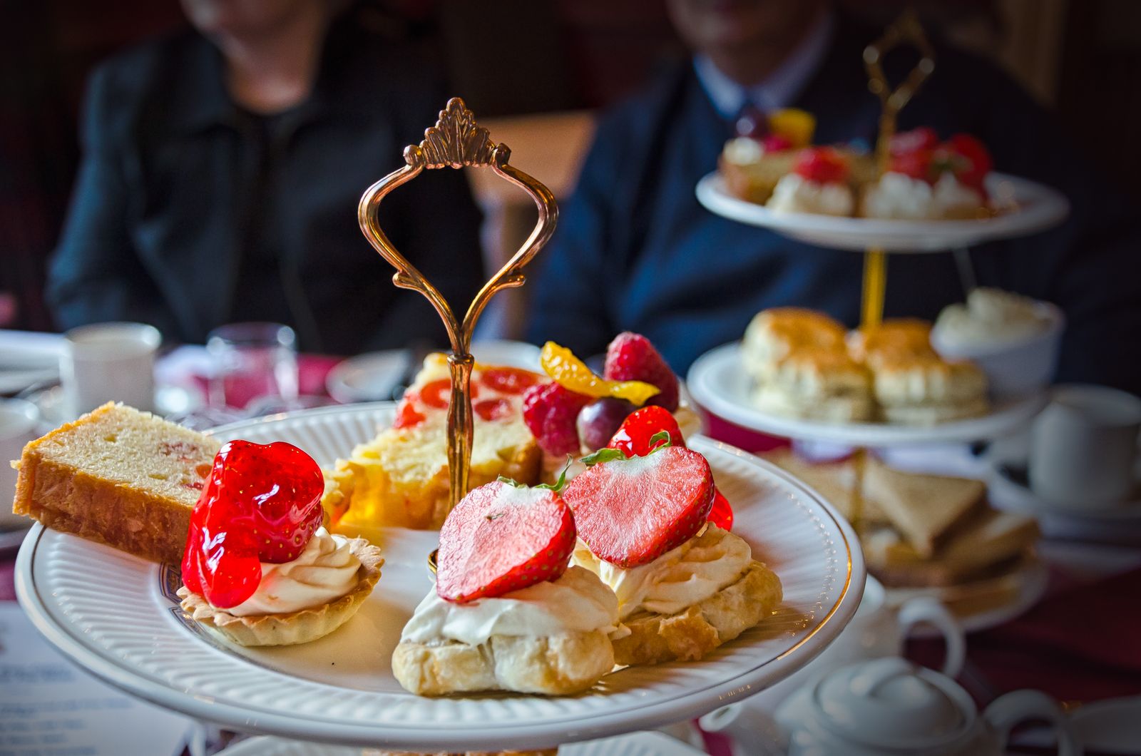 A three-tier afternoon tea stand with sandwiches, scones and little cakes