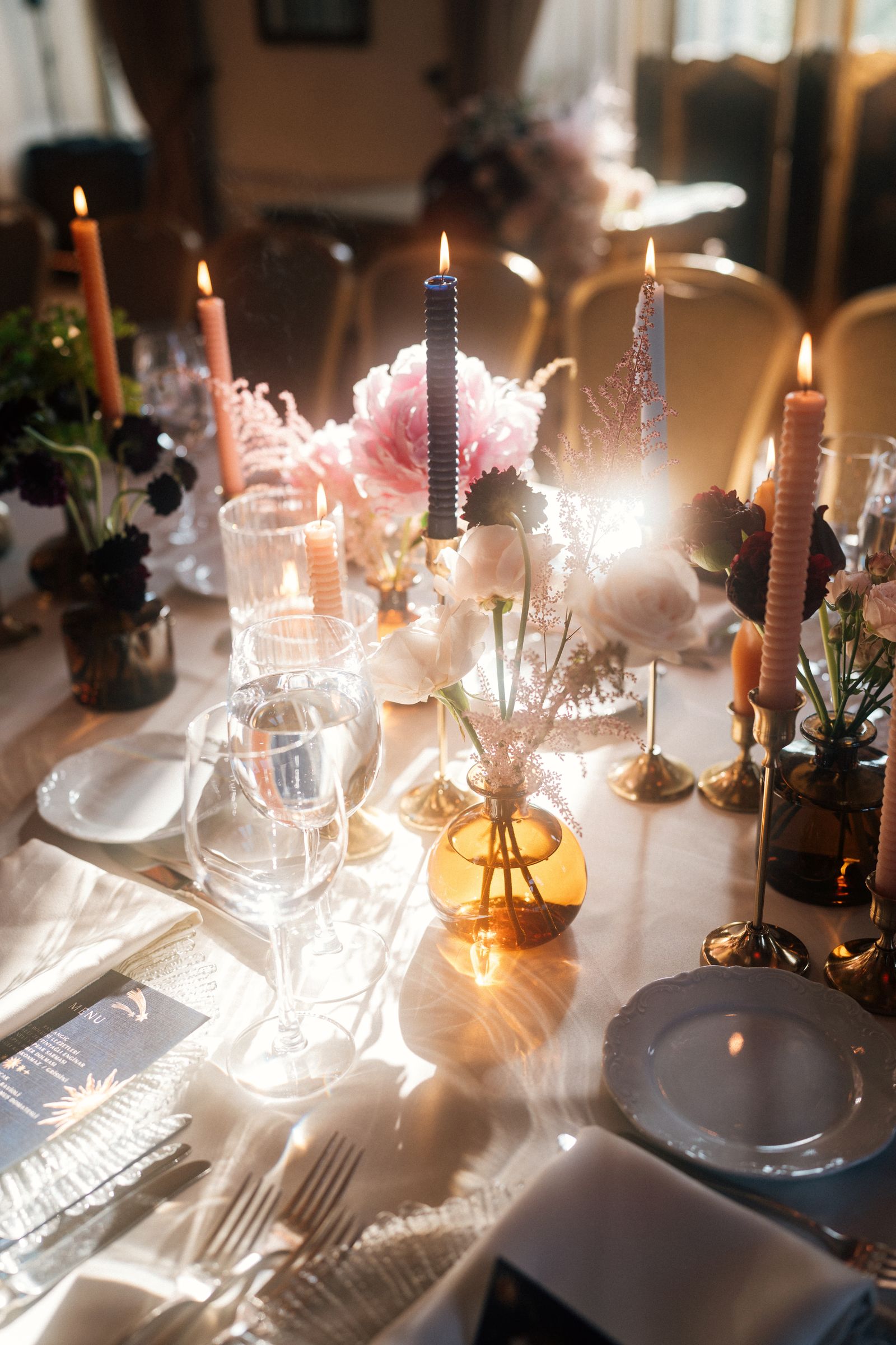 A long wedding table with flowers, candles and string lights