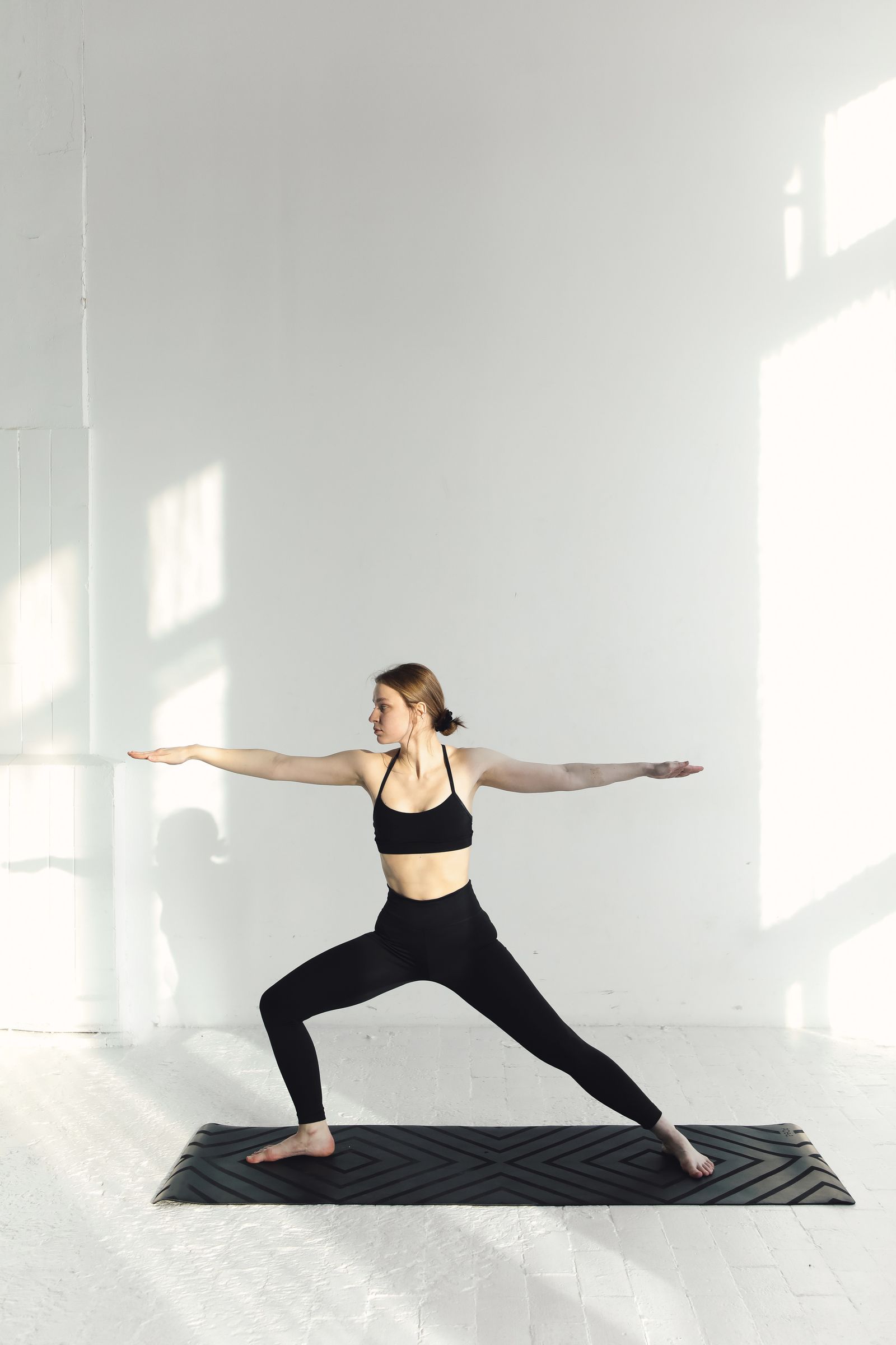 Woman practising yoga on a mat in a bright, calm studio
