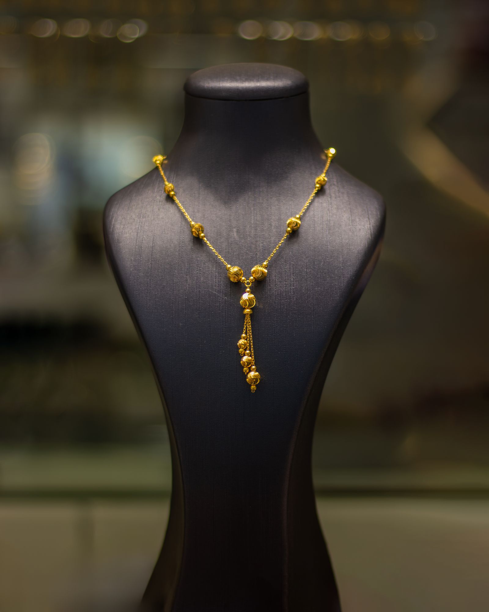 A gold necklace with a pendant on a display bust
