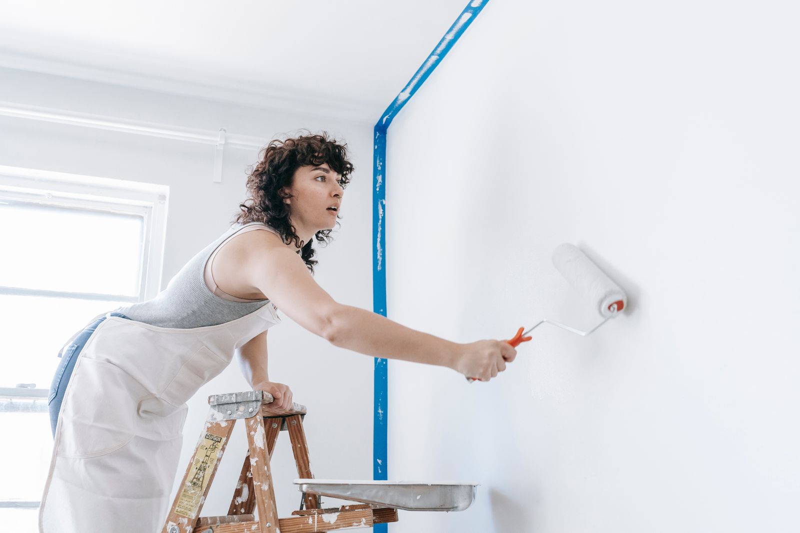 A painter rolling a fresh colour onto a living room wall