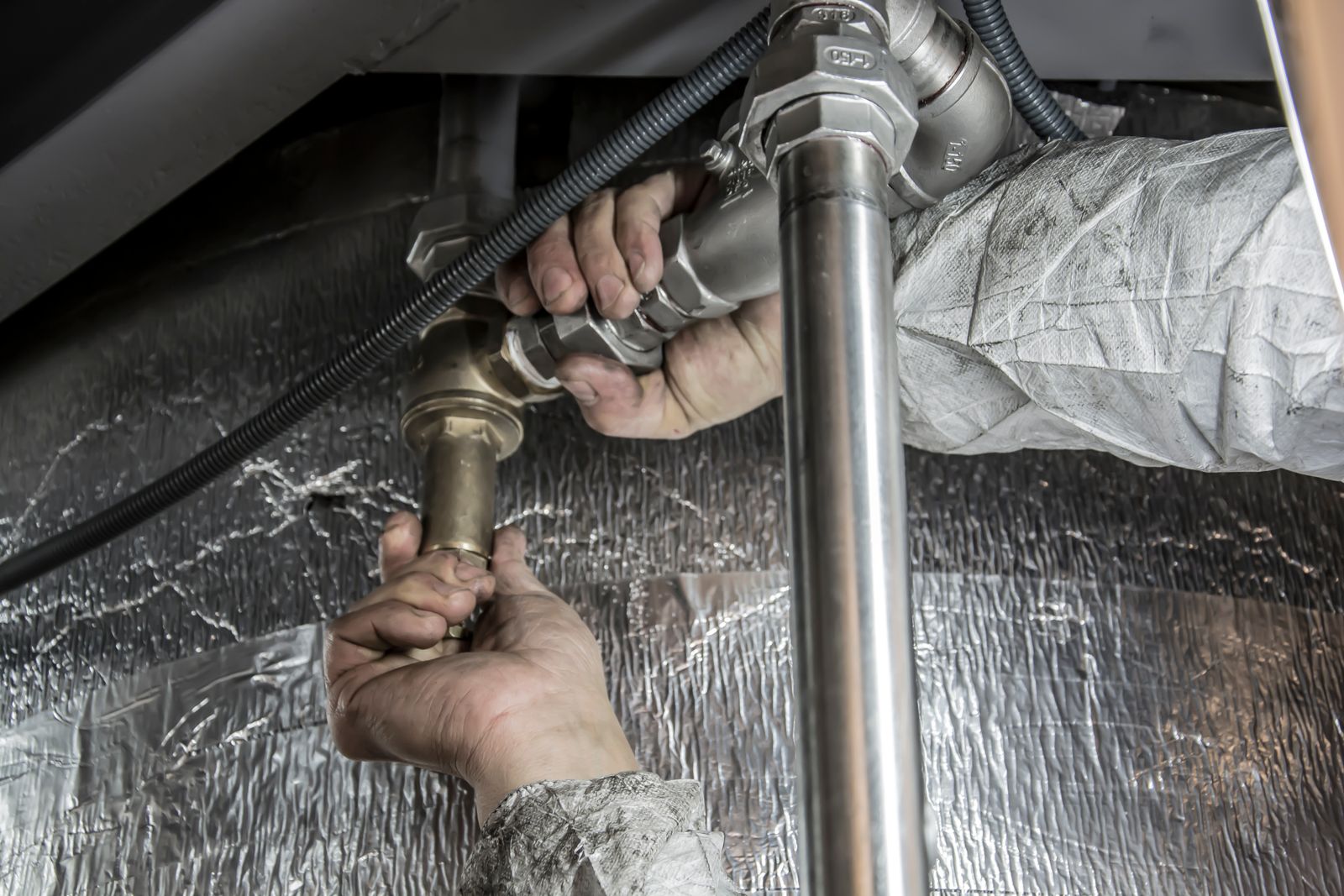 A plumber fixing the pipes under a kitchen sink