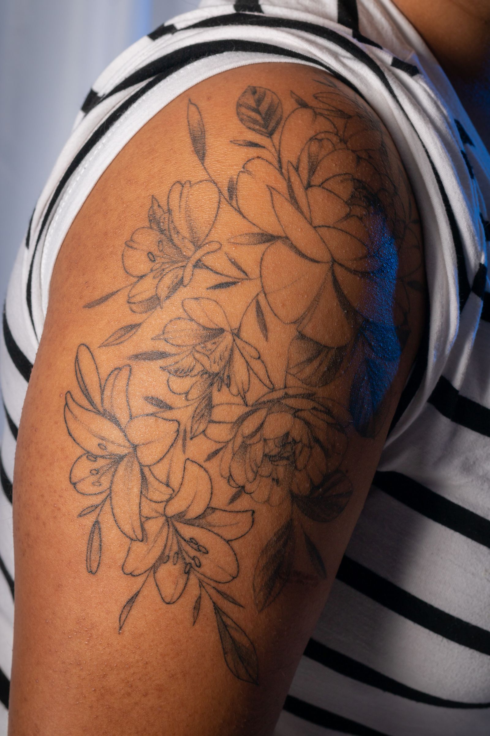 A fine line floral tattoo on an upper arm