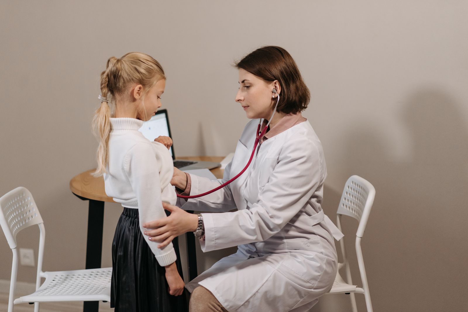 A children’s doctor with a young child holding a teddy bear