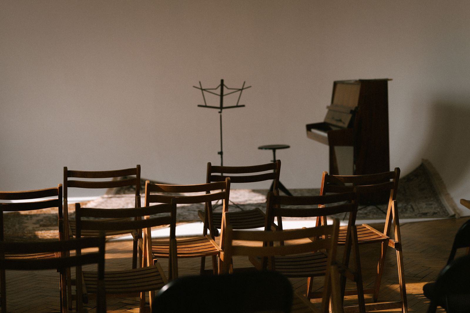 A small recital: a grand piano on a low stage and rows of chairs