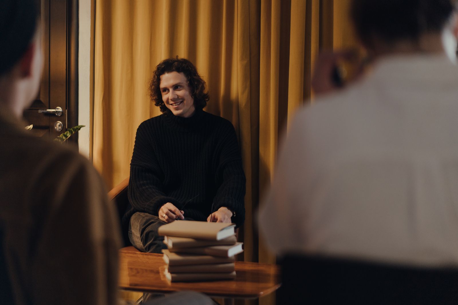 An author reading to an audience in a bookshop, seen from the back of the room