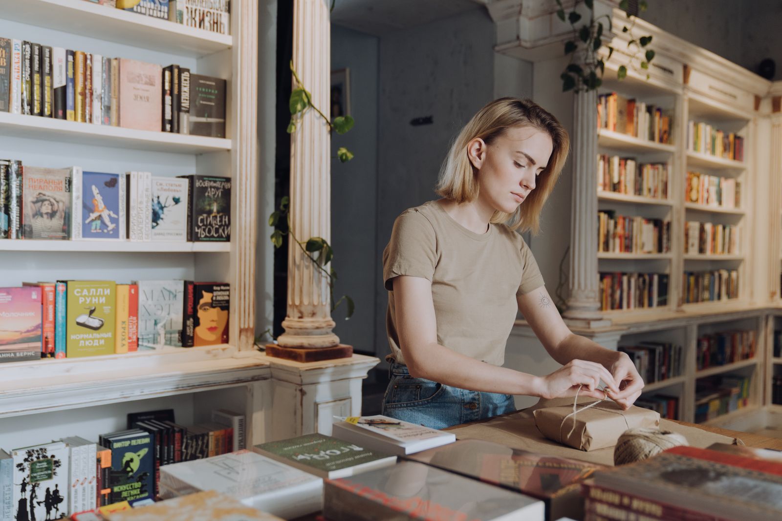 Inside the bookshop: tall wooden shelves, a front table of new books and the counter