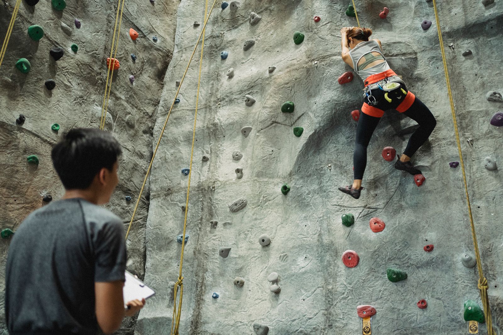 A route setter standing in front of a climbing wall, holding a new hold