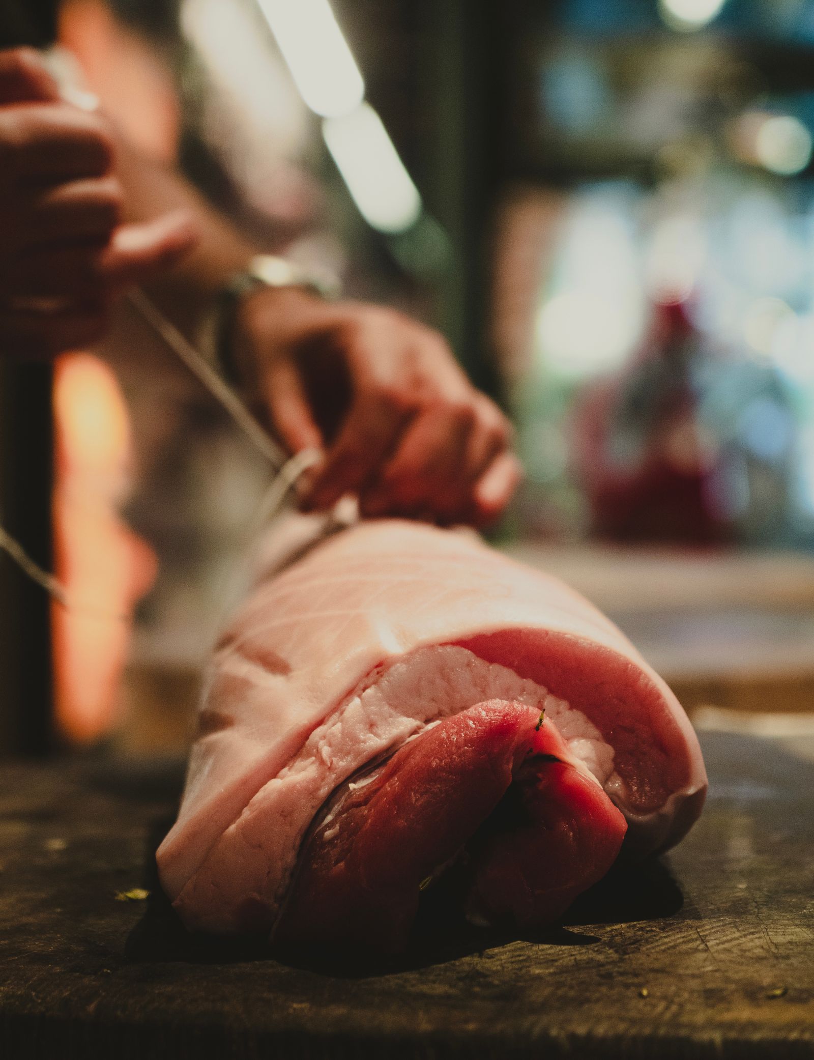 A butcher tying a rolled roast with string