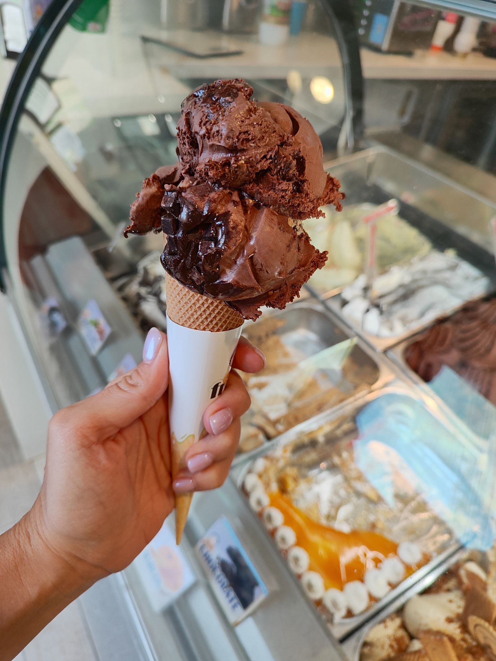 A hand holding up a cone with two scoops of gelato