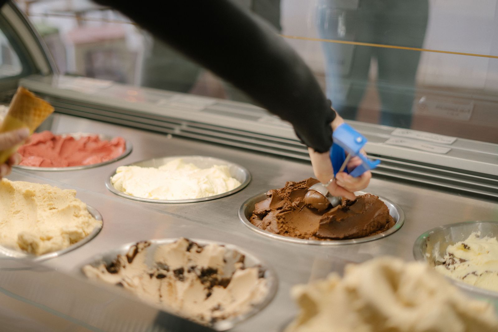 A steel spade lifting gelato out of a tub in the counter