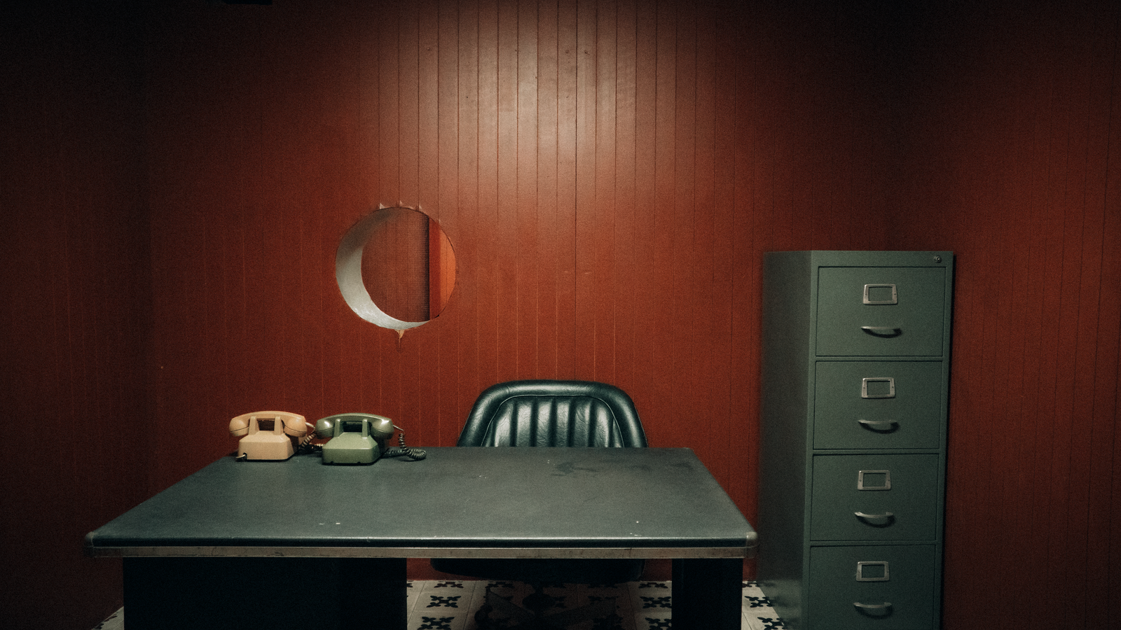 A detective’s office with a desk, two old telephones and a filing cabinet