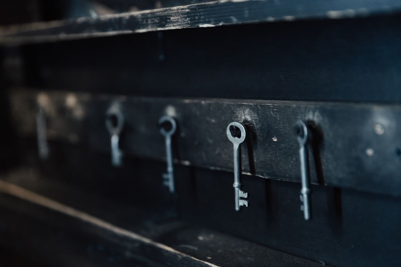 Old keys hanging in a row on a dark wall