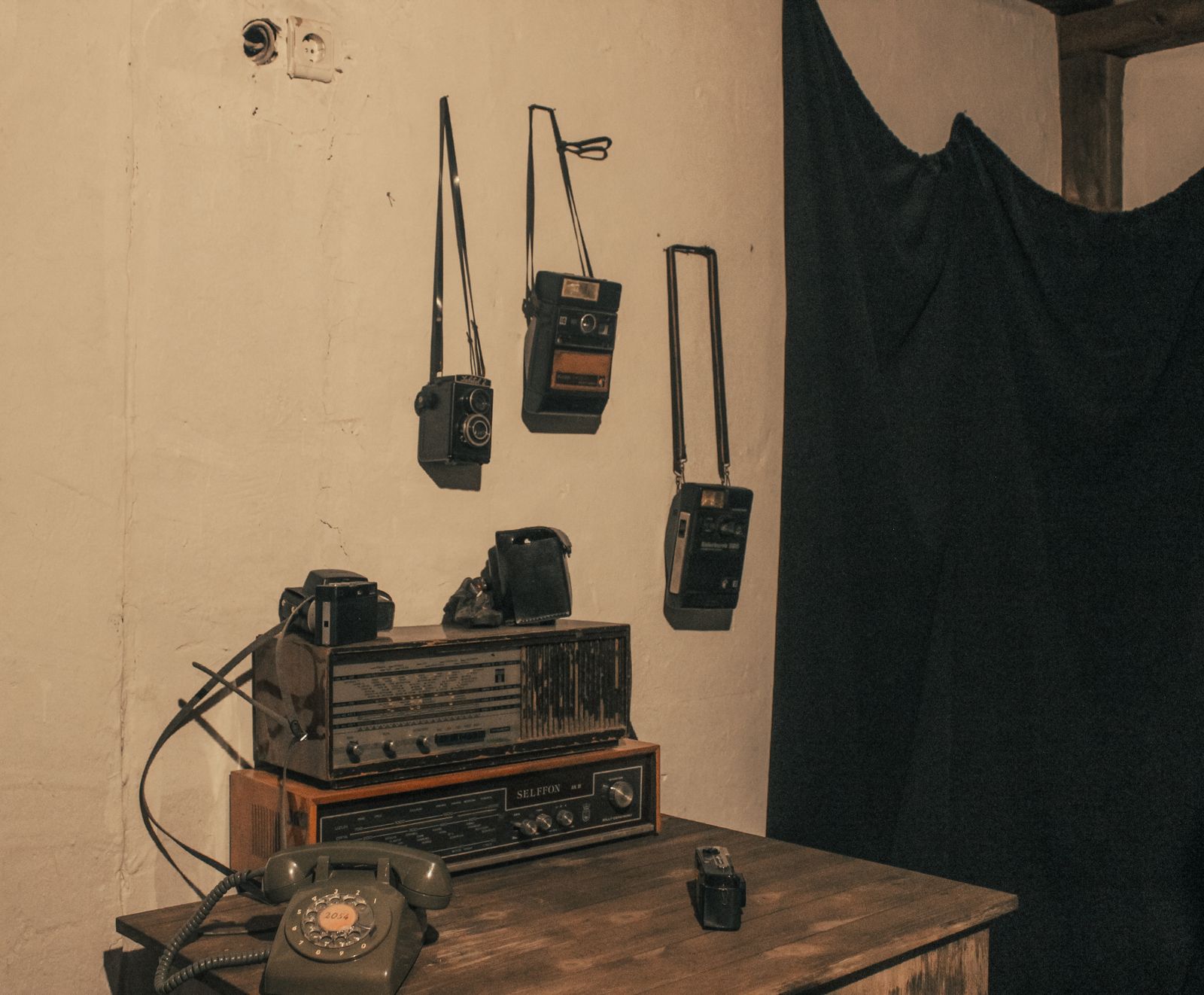 A radio room with an old receiver, cameras and a telephone on a wooden table