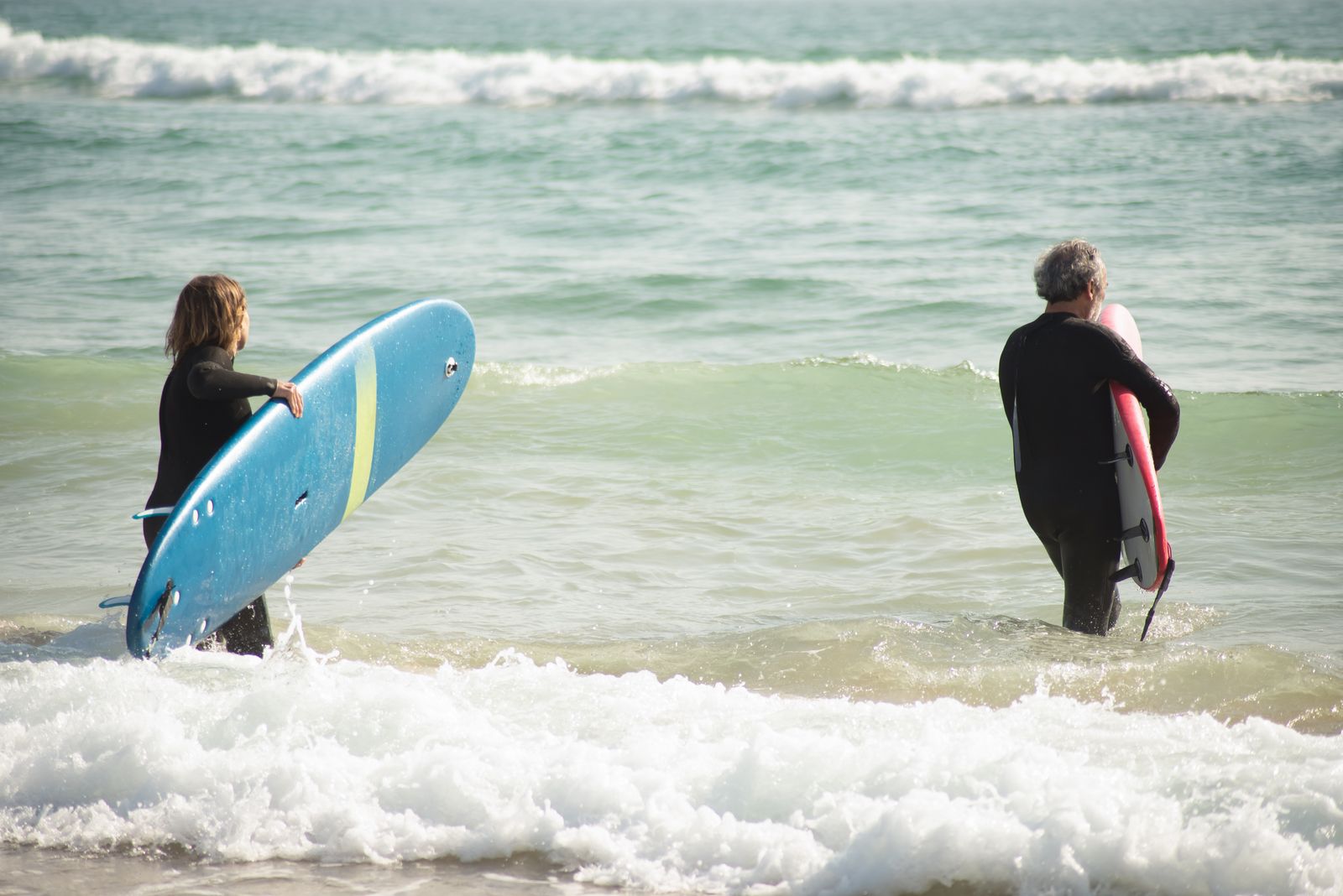 Four learners walking to the water with their boards