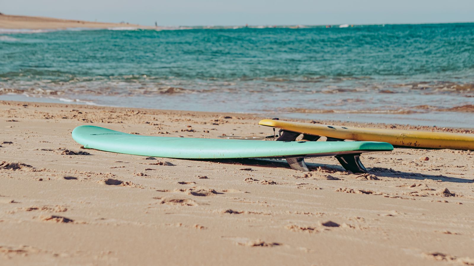 Soft-top boards lying on the sand before a lesson