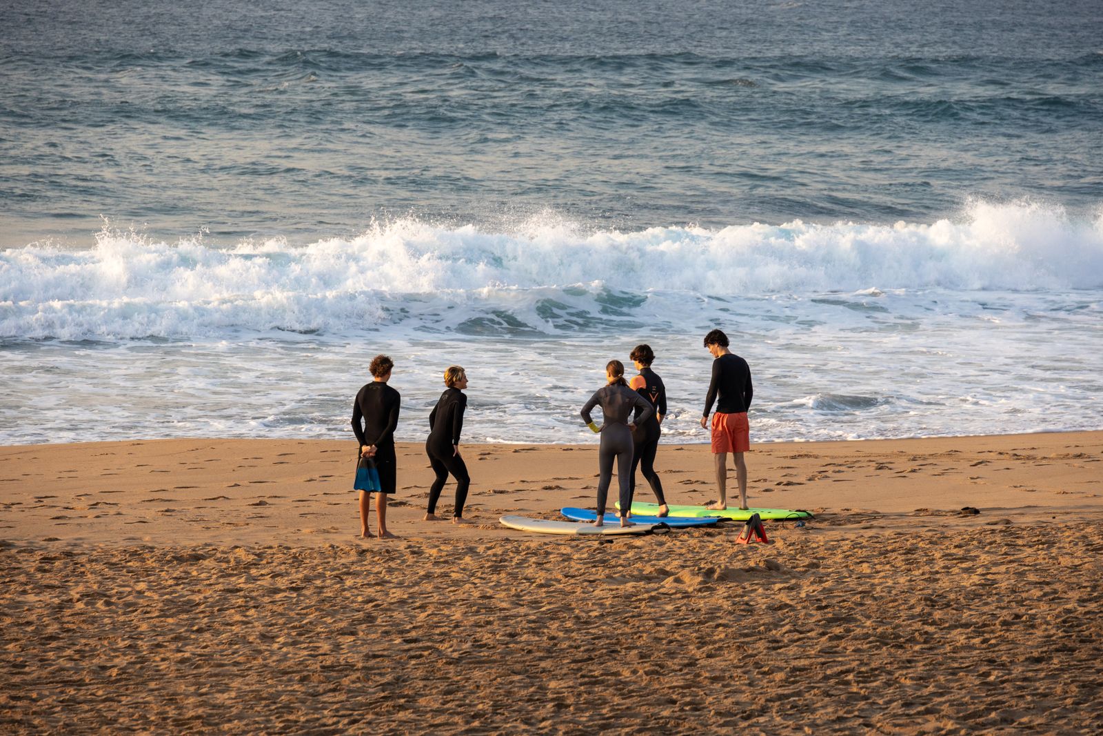 An instructor and three learners practising on their boards on the sand