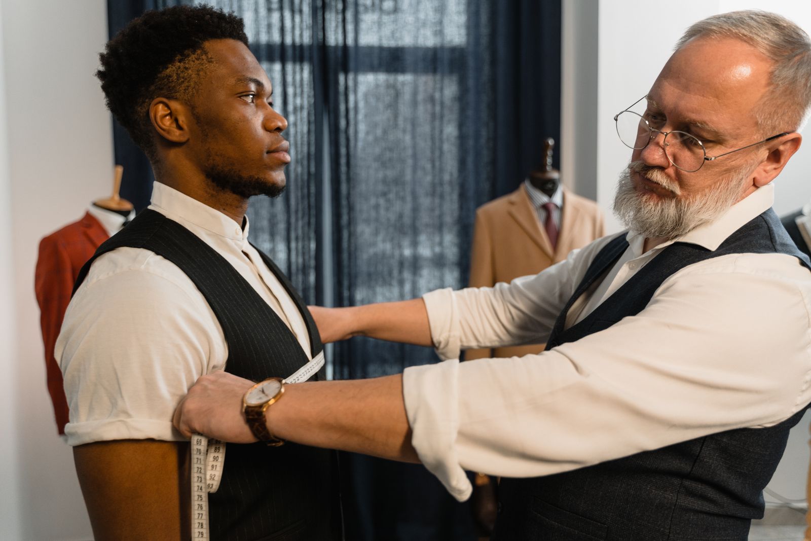 A tailor measuring the sleeve of a jacket with a tape measure