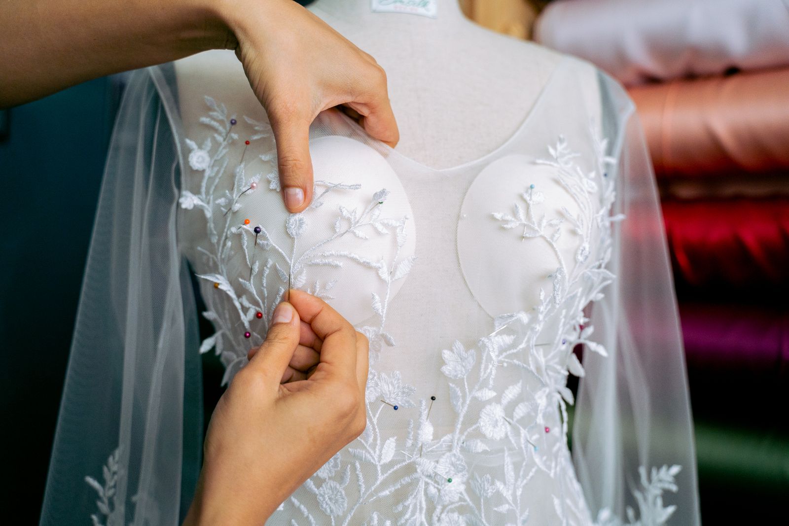 A wedding dress on a dress form, pinned for a fitting