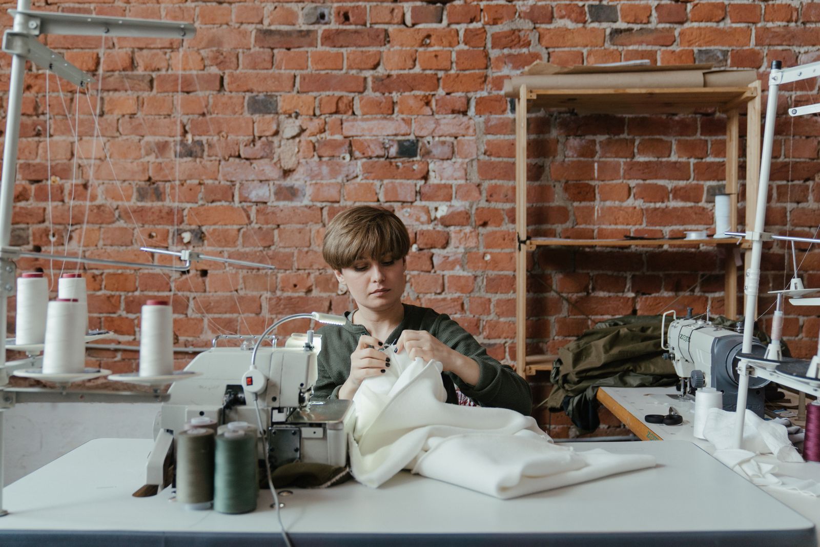 The workroom: a sewing machine on the cutting table, rolls of cloth on a shelf and a jacket on a dress form